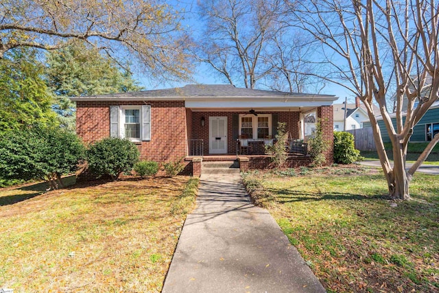 bungalow-style house featuring brick siding, covered porch, a ceiling fan, and a front yard