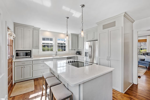 kitchen featuring a breakfast bar, a sink, a kitchen island, wood finished floors, and appliances with stainless steel finishes