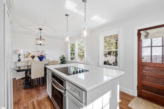 kitchen with oven, decorative light fixtures, a kitchen island, dark wood-style floors, and black electric cooktop