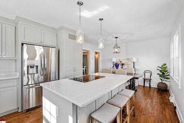 kitchen featuring visible vents, dark wood-type flooring, a center island, and stainless steel refrigerator with ice dispenser