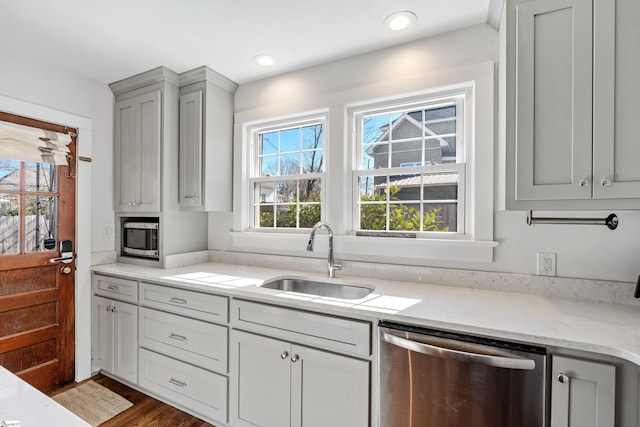 kitchen with dark wood-type flooring, a sink, light stone counters, recessed lighting, and stainless steel appliances