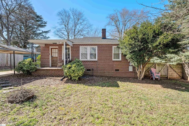 rear view of property with a lawn, fence, brick siding, and crawl space