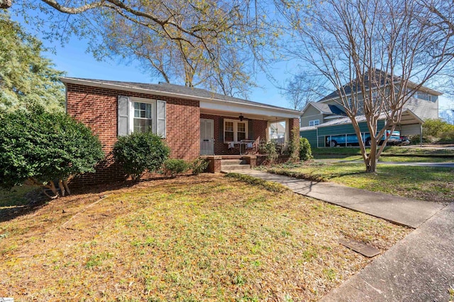 ranch-style house featuring a ceiling fan, brick siding, covered porch, and a front lawn