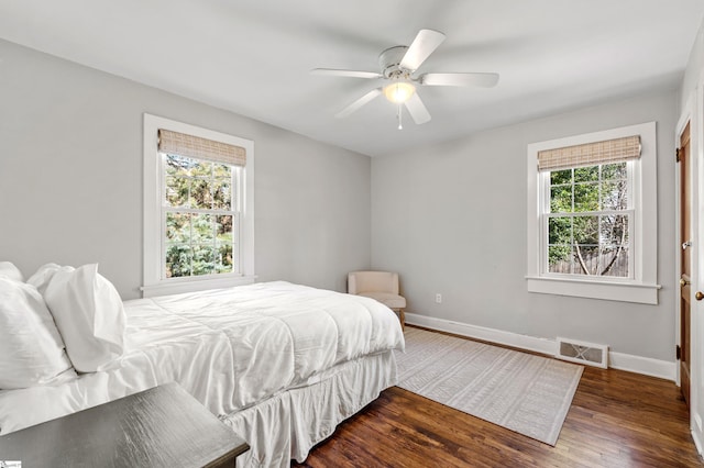 bedroom with visible vents, baseboards, wood finished floors, and a ceiling fan