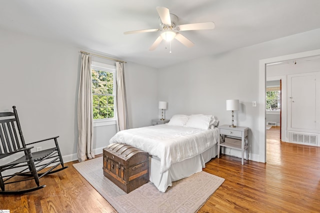 bedroom with visible vents, a ceiling fan, baseboards, and wood finished floors