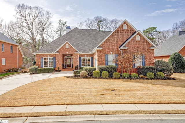 view of front of home featuring a front lawn, brick siding, roof with shingles, and a chimney