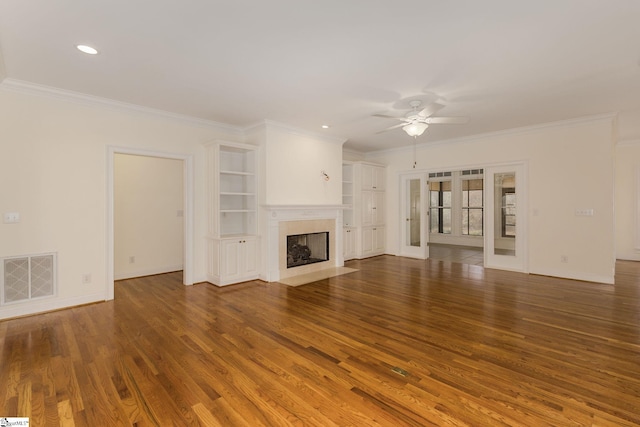 unfurnished living room featuring visible vents, ornamental molding, a premium fireplace, french doors, and wood finished floors