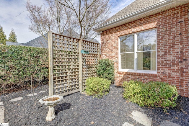 view of side of home with brick siding and a shingled roof