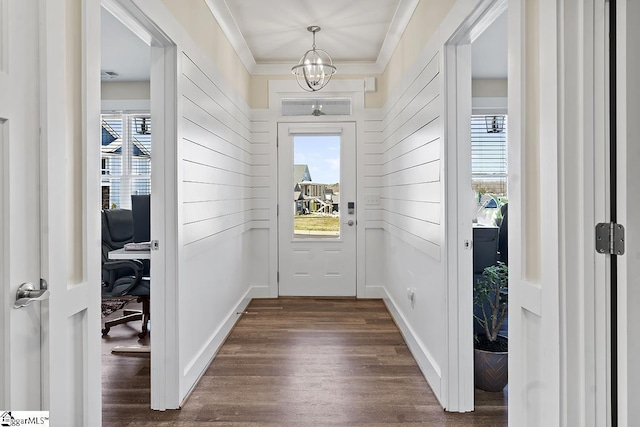 doorway to outside featuring dark wood finished floors, an inviting chandelier, baseboards, and ornamental molding