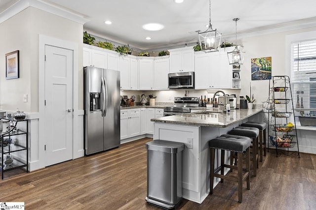 kitchen with a kitchen bar, ornamental molding, a sink, appliances with stainless steel finishes, and a peninsula