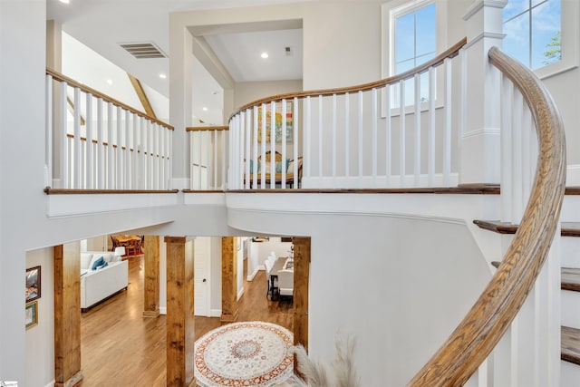 stairway with visible vents, wood finished floors, recessed lighting, a towering ceiling, and ornate columns