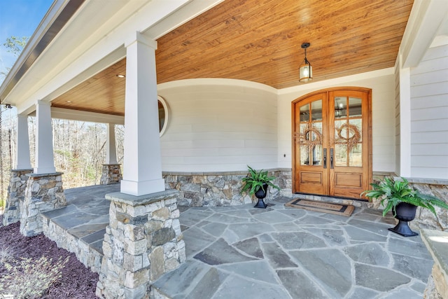 view of exterior entry with a porch and french doors