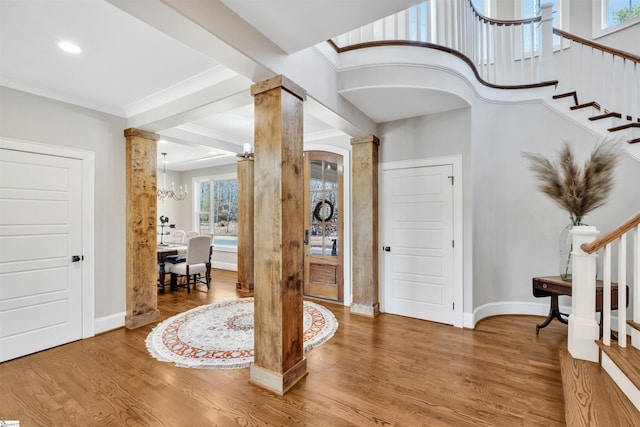 foyer entrance featuring baseboards, stairs, ornate columns, and wood finished floors