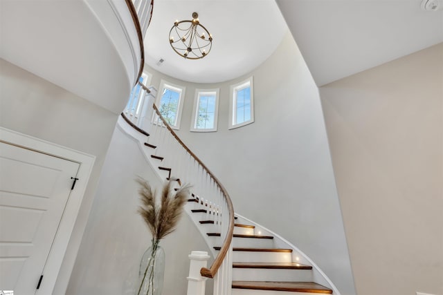 staircase featuring a high ceiling and an inviting chandelier