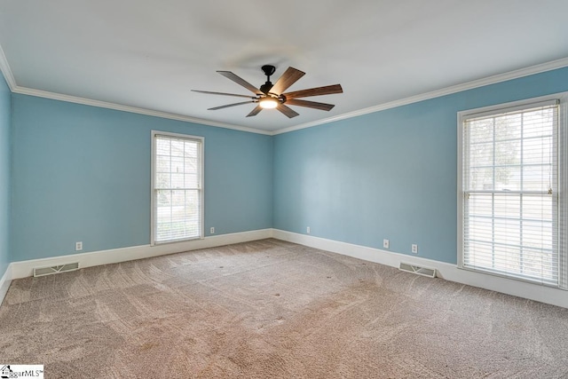 carpeted spare room featuring visible vents, baseboards, a ceiling fan, and ornamental molding