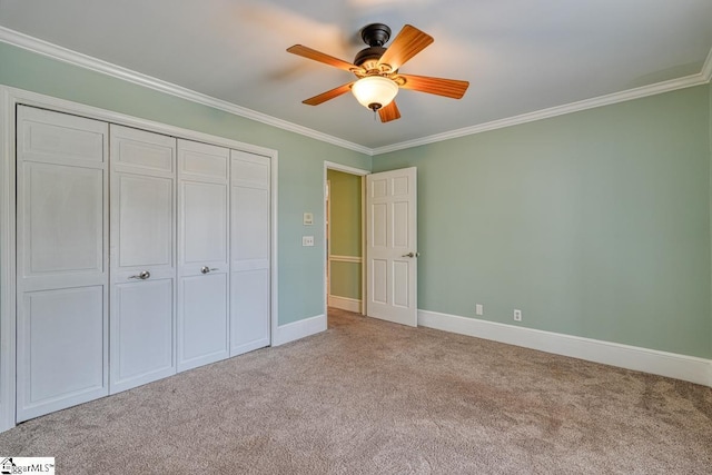 unfurnished bedroom with ceiling fan, baseboards, ornamental molding, carpet floors, and a closet