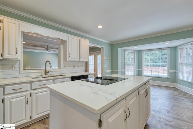 kitchen featuring a sink, black electric stovetop, a kitchen island, and light wood-style flooring