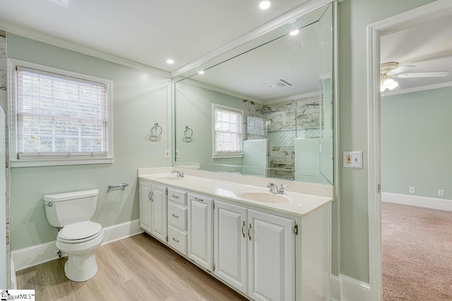 full bathroom featuring a sink, toilet, ornamental molding, and a tile shower