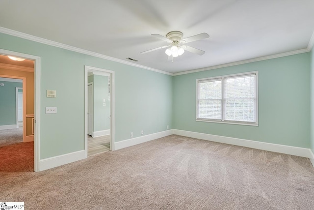 empty room featuring carpet flooring, visible vents, baseboards, and ornamental molding