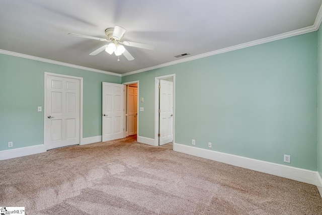 unfurnished bedroom with visible vents, crown molding, ceiling fan, baseboards, and carpet