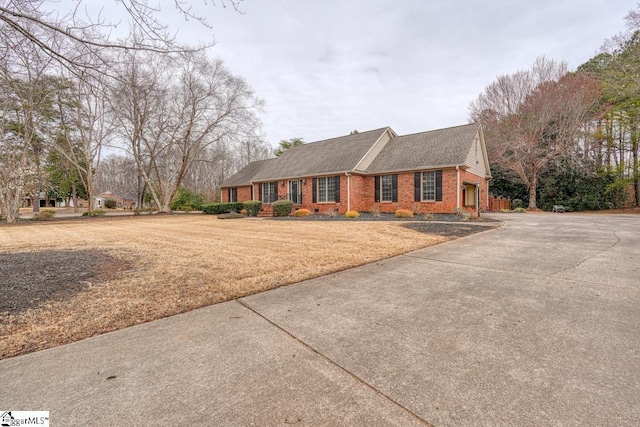 view of front of house featuring a front yard, brick siding, and a shingled roof