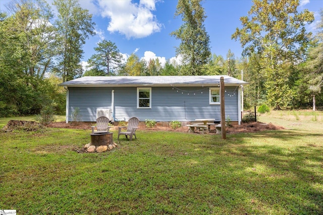 rear view of property with crawl space, an outdoor fire pit, and a yard