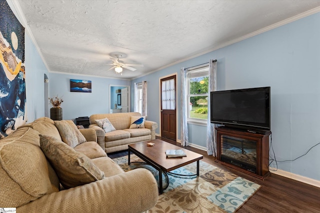 living room with crown molding, ceiling fan, baseboards, wood finished floors, and a textured ceiling