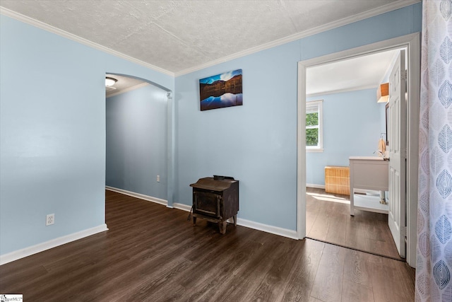 empty room featuring baseboards, ornamental molding, wood finished floors, arched walkways, and a textured ceiling