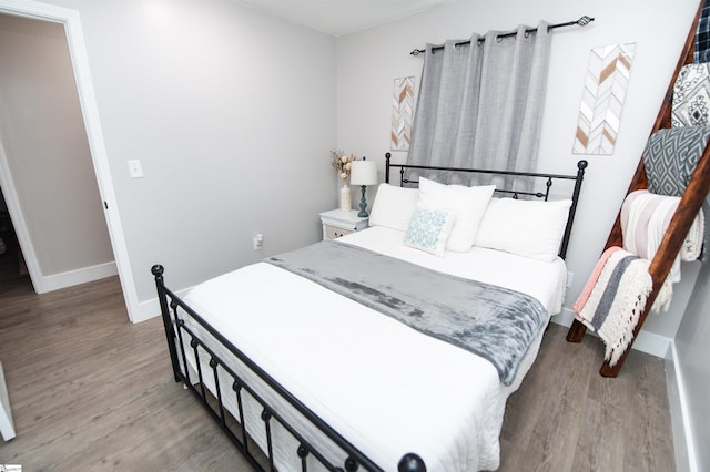 bedroom featuring baseboards and wood finished floors