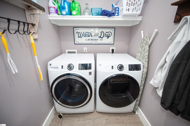 laundry room featuring baseboards, separate washer and dryer, wood finished floors, and laundry area