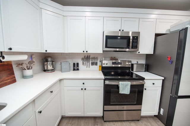 kitchen featuring stainless steel appliances, white cabinets, decorative backsplash, and light wood finished floors