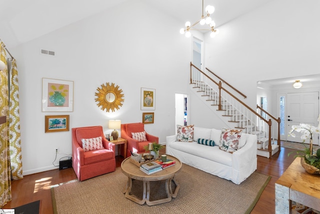 living room featuring visible vents, wood finished floors, baseboards, a chandelier, and stairs