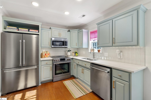 kitchen featuring visible vents, a sink, appliances with stainless steel finishes, light wood finished floors, and decorative backsplash