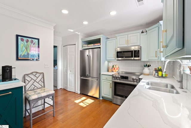 kitchen with visible vents, a sink, backsplash, stainless steel appliances, and light wood finished floors