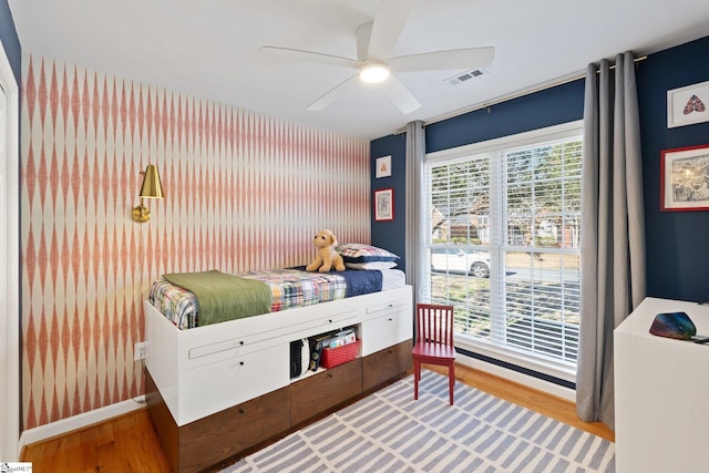 bedroom featuring light wood finished floors, visible vents, multiple windows, and ceiling fan