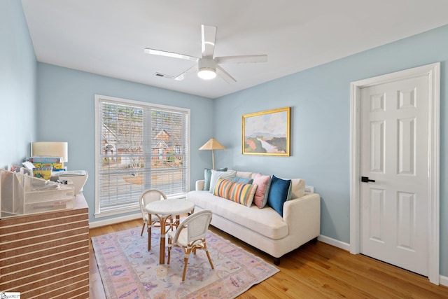 living area featuring visible vents, baseboards, light wood-type flooring, and ceiling fan