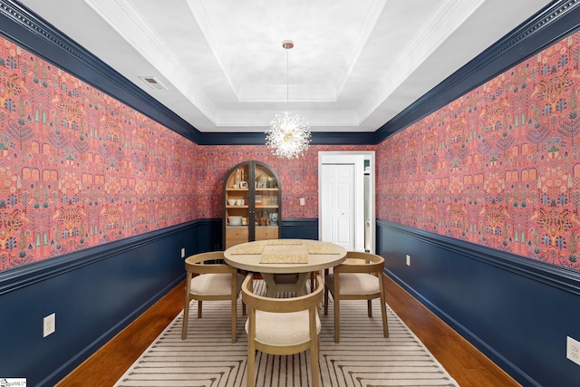 dining room with a tray ceiling, a wainscoted wall, and hardwood / wood-style flooring