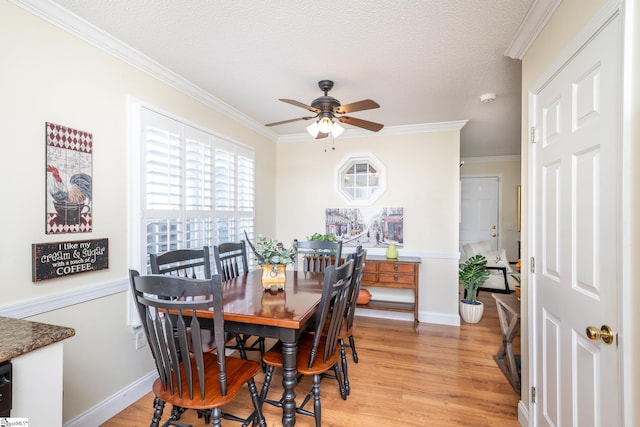 dining space featuring light wood finished floors, a textured ceiling, a ceiling fan, and ornamental molding