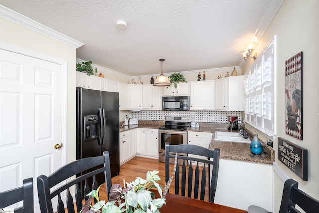 kitchen with black appliances, white cabinets, crown molding, and a sink