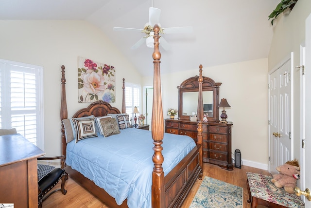 bedroom with baseboards, lofted ceiling, light wood-style floors, a closet, and a ceiling fan