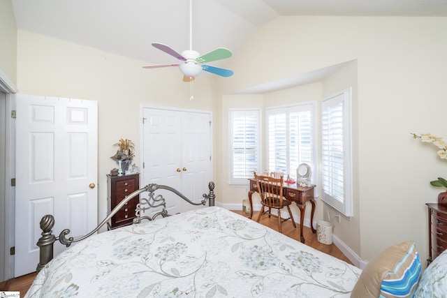 bedroom featuring baseboards, vaulted ceiling, wood finished floors, a closet, and a ceiling fan