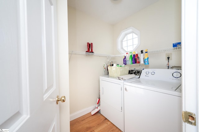 washroom featuring washer and dryer, laundry area, light wood-style floors, and baseboards