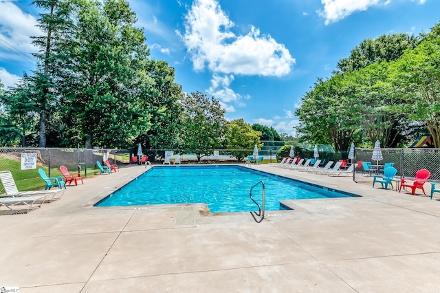 community pool with a patio and fence