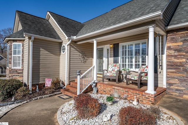 entrance to property with stone siding, a porch, and a shingled roof