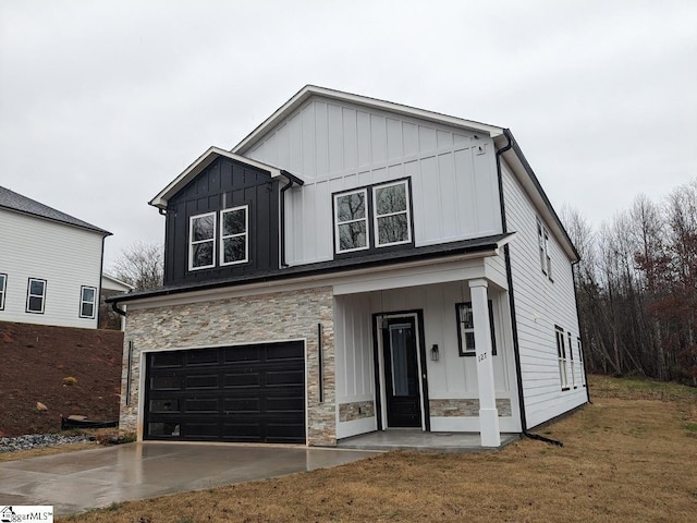 modern farmhouse style home featuring a front lawn, stone siding, board and batten siding, concrete driveway, and an attached garage