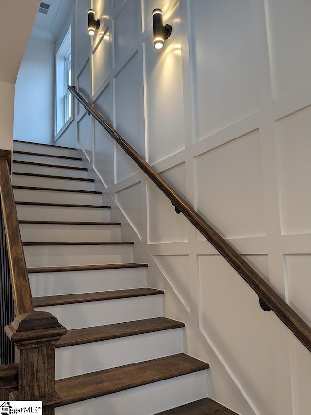 staircase with a decorative wall and visible vents