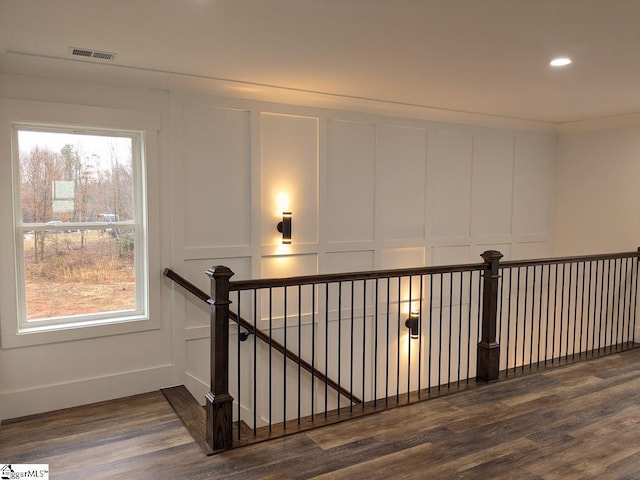 stairs with visible vents, a healthy amount of sunlight, wood finished floors, and a decorative wall