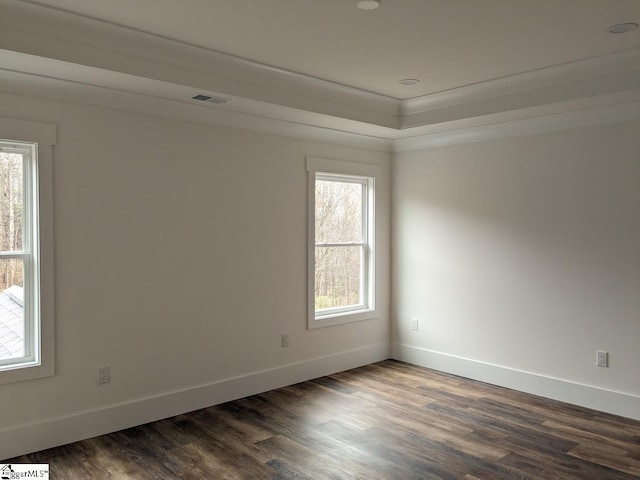 spare room featuring a tray ceiling, visible vents, baseboards, and dark wood-style floors