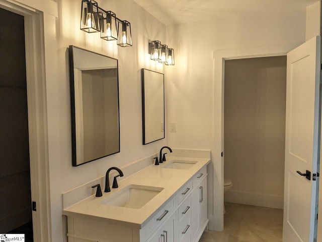 full bath featuring a sink, baseboards, toilet, and double vanity