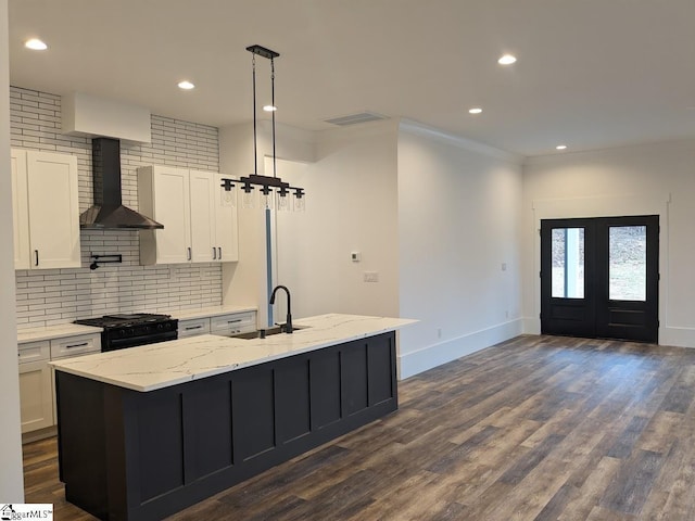 kitchen featuring a sink, wall chimney exhaust hood, white cabinets, and gas stove